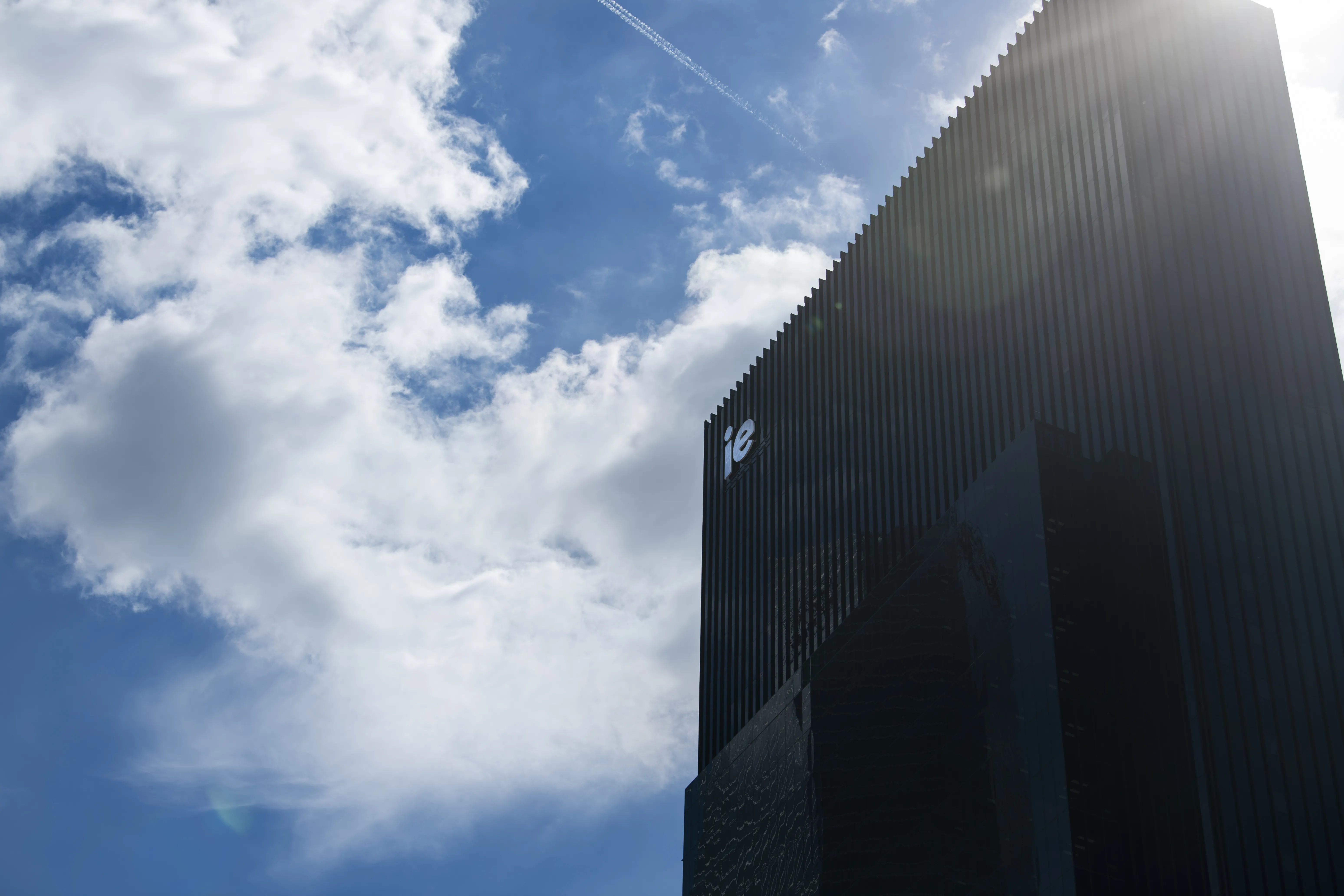 Fachada acristalada del IE Tower reflejando el cielo de Madrid
